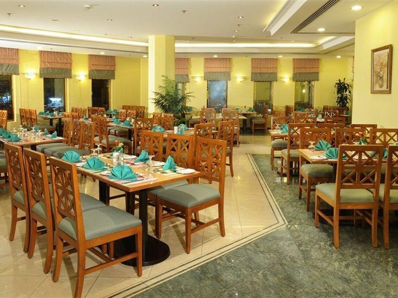 Makarem Ajyad Makkah Hotel Mecca Exterior photo The photo shows an interior view of a restaurant. It features wooden tables and chairs arranged neatly throughout the space. Each table is set with turquoise napkins, contributing to the overall decor. The walls are painted a soft yellow, and there a