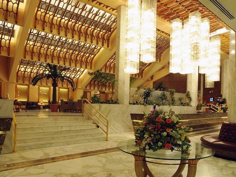 Makarem Ajyad Makkah Hotel Mecca Exterior photo The photo shows a luxurious hotel lobby with elegant design features. It has high ceilings adorned with wooden beams and large, decorative light fixtures hanging from above. The lobby is brightly lit, creating a warm and inviting atmosphere. There ar